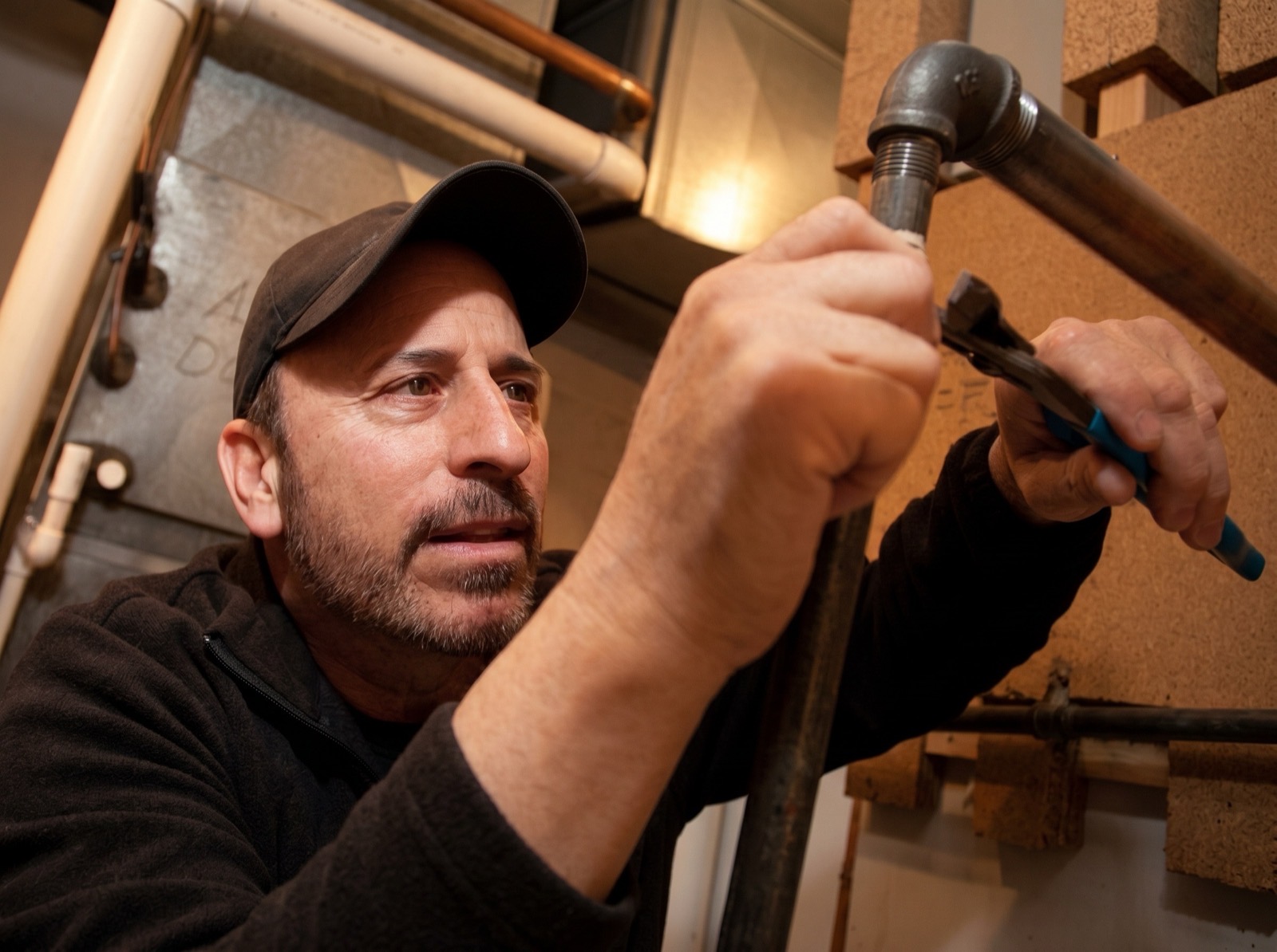 Dino Tori, owner of Countryside Plumbing, working on a pipe in a Milford basement
